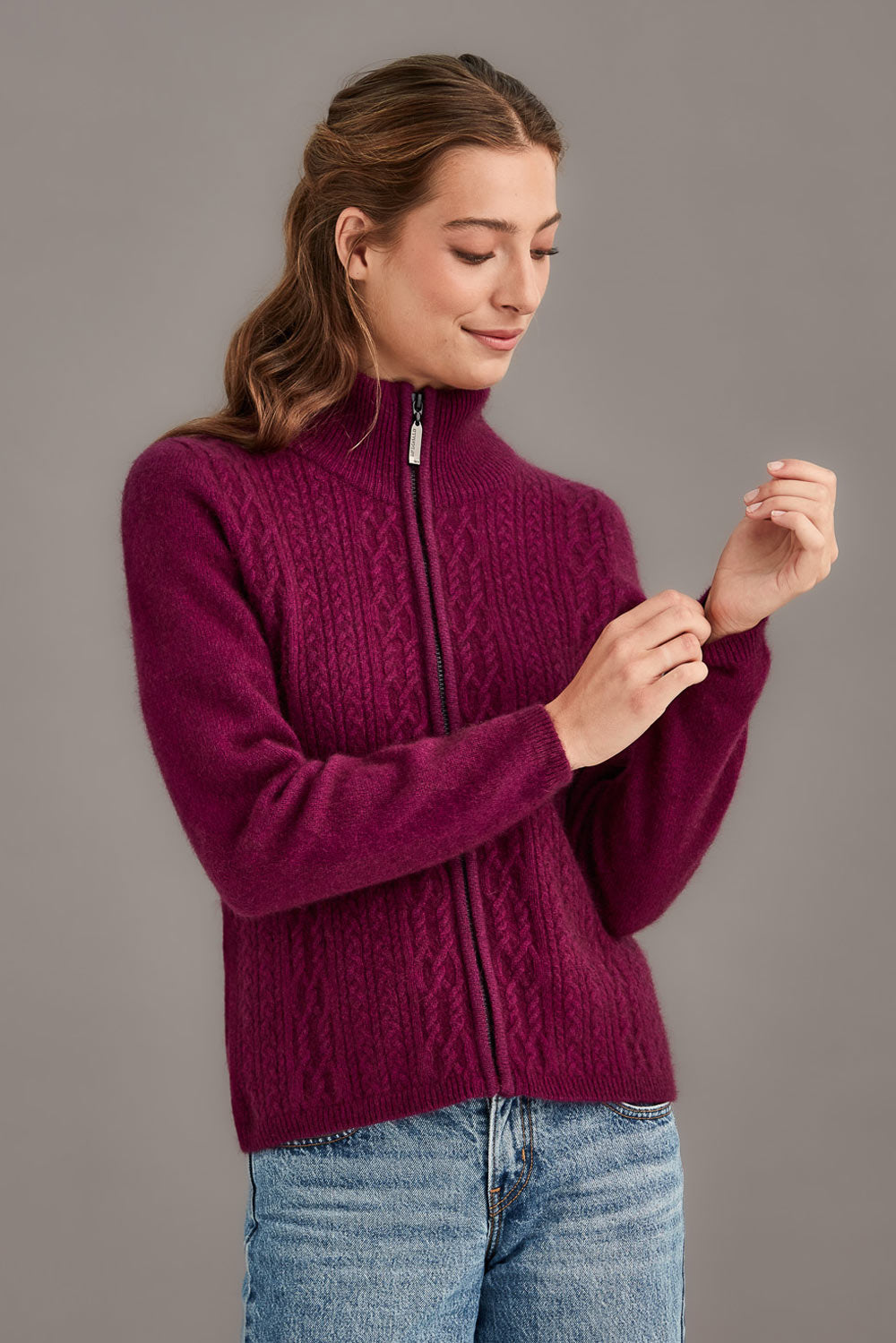 Woman wearing a berry sweater with a zipper on a gray background