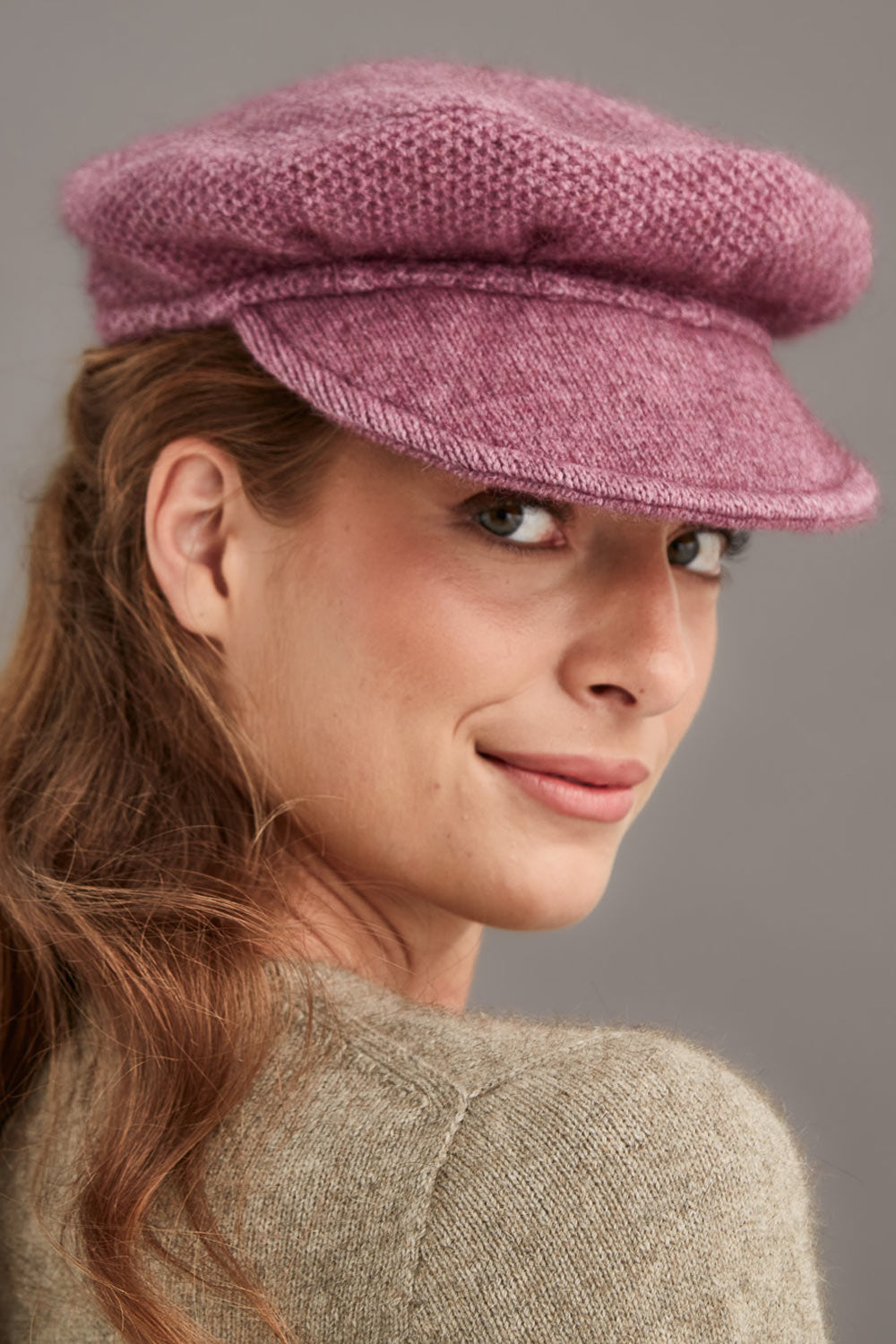 Woman wearing a pink knitted cap against a gray background