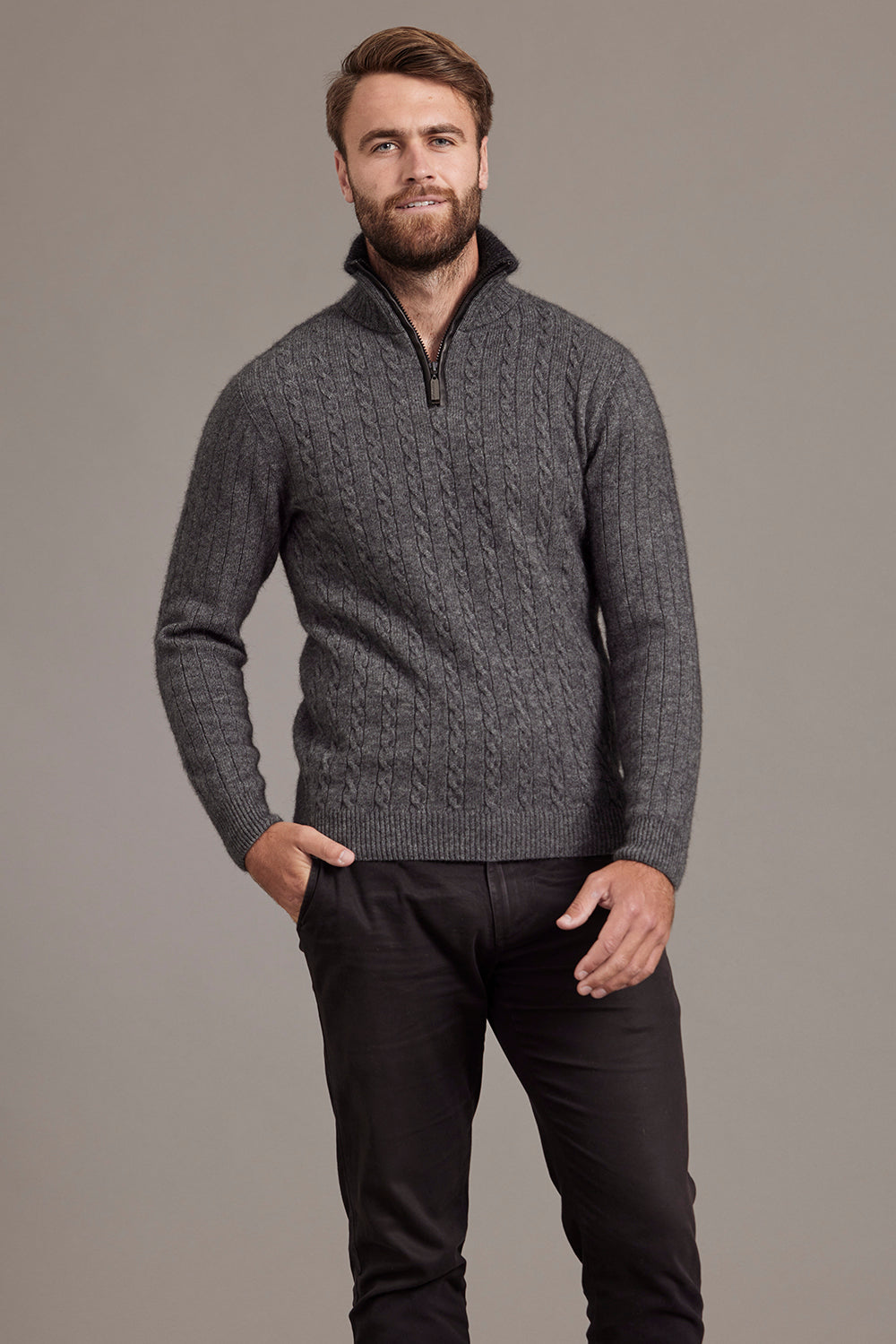 A man wearing a pewter grey cable knit jersey with contrast trim standing outdoors.