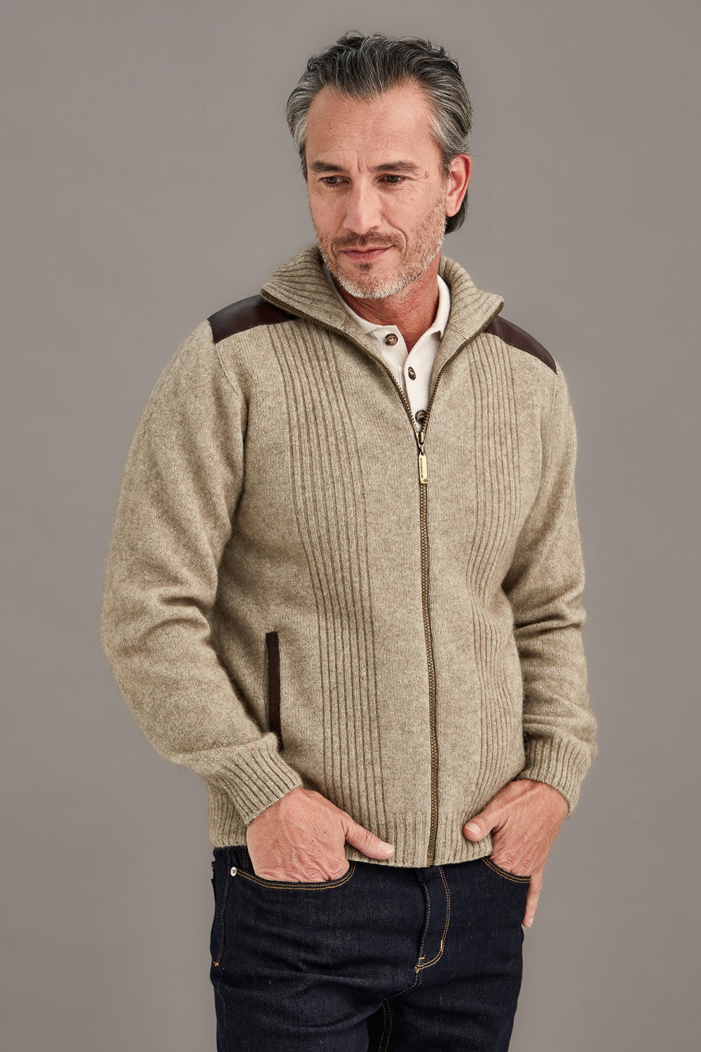 Man wearing a beige zip-up jacket with brown accents on a gray background