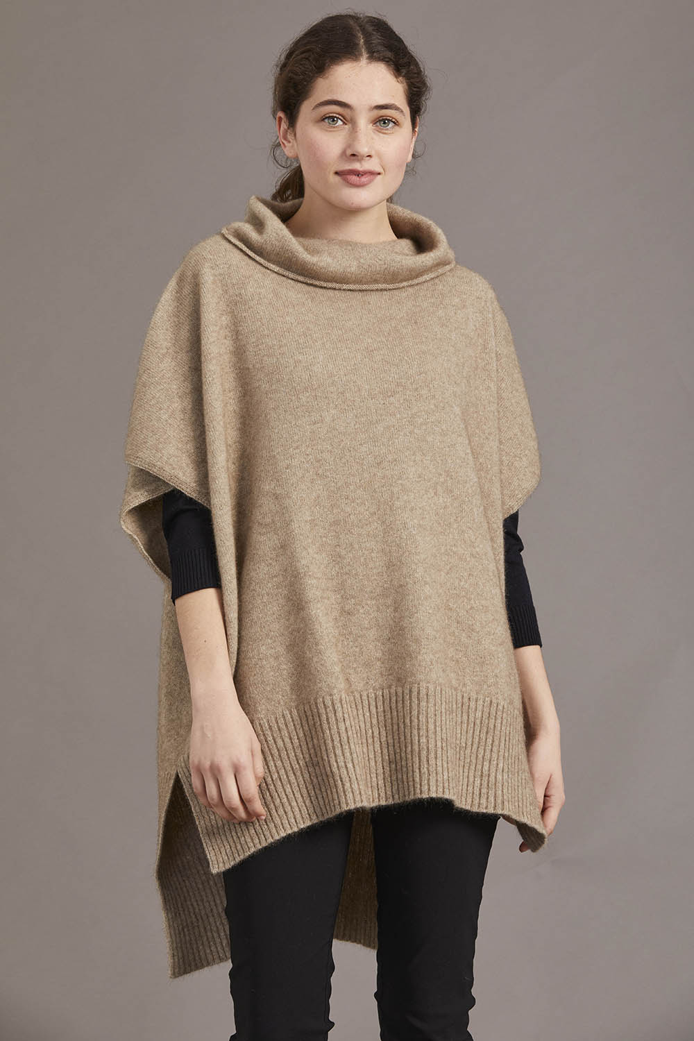 A model wearing a mocha poncho with a cowl neck and a step level hem, standing against a neutral background.
