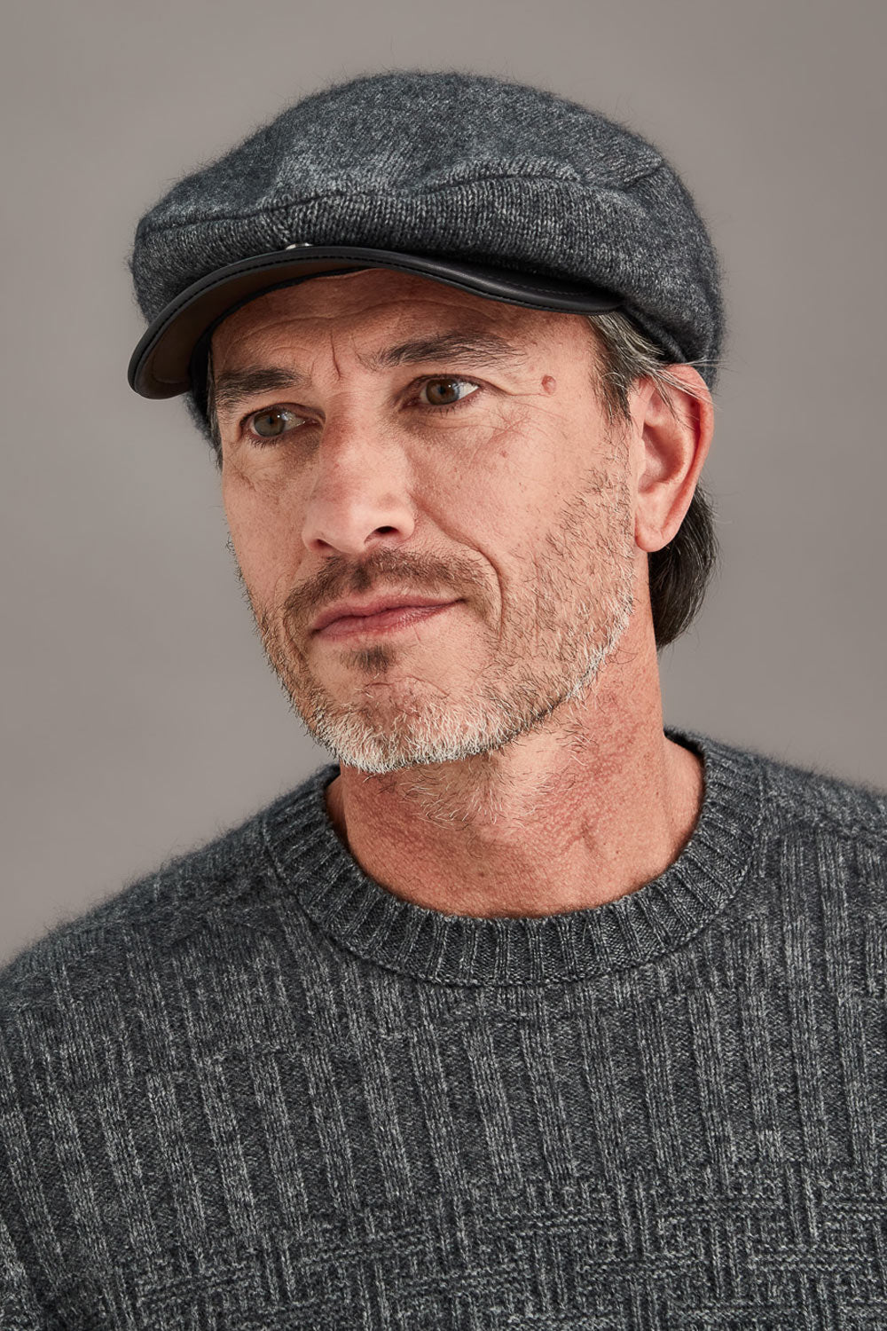 Man wearing a gray cap and sweater against a plain background
